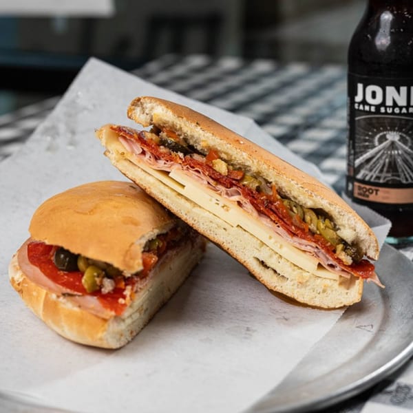 Two halves of a SENECA’S ITALIAN DELI & MARKET sub sandwich with meat, cheese, and olives.